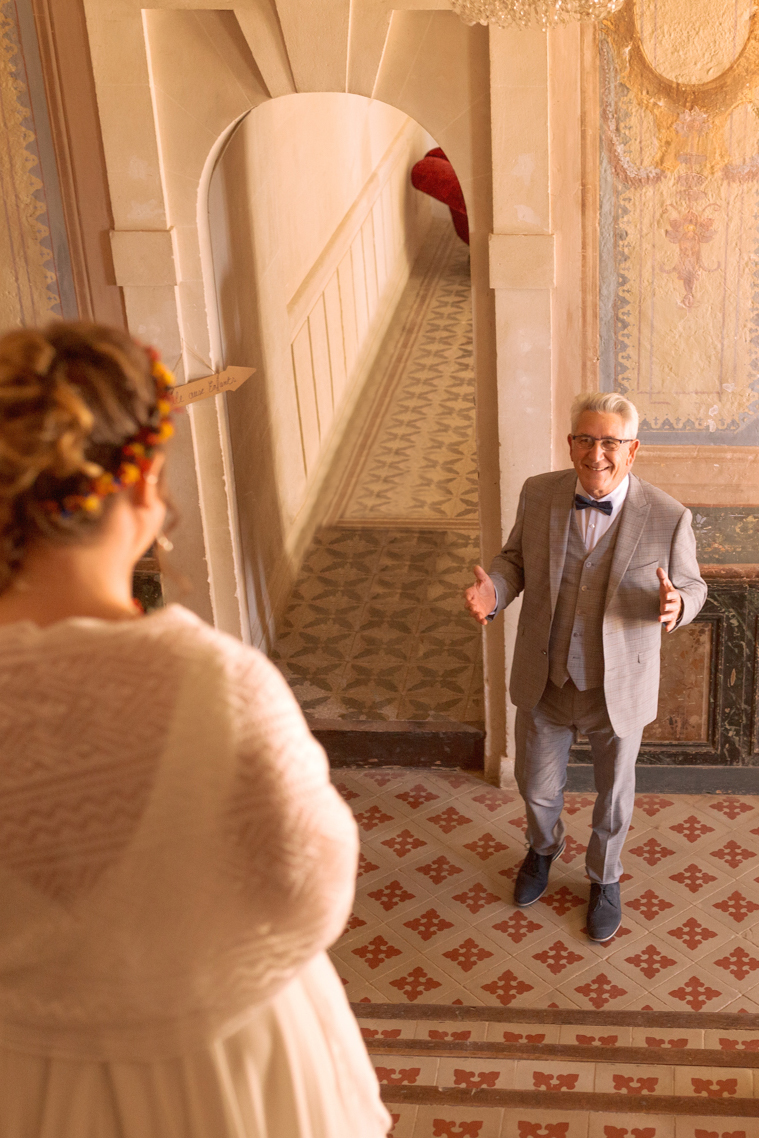 La mariée descend un escalier vers un homme ému, probablement son père.